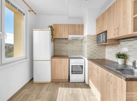 Moderní kuchyň s dřevěnými skříňkami, parketovou podlahou a velkými okny nabízí světlý prostor pro vaření. | Pronájem bytu, 1+1, 32 m²