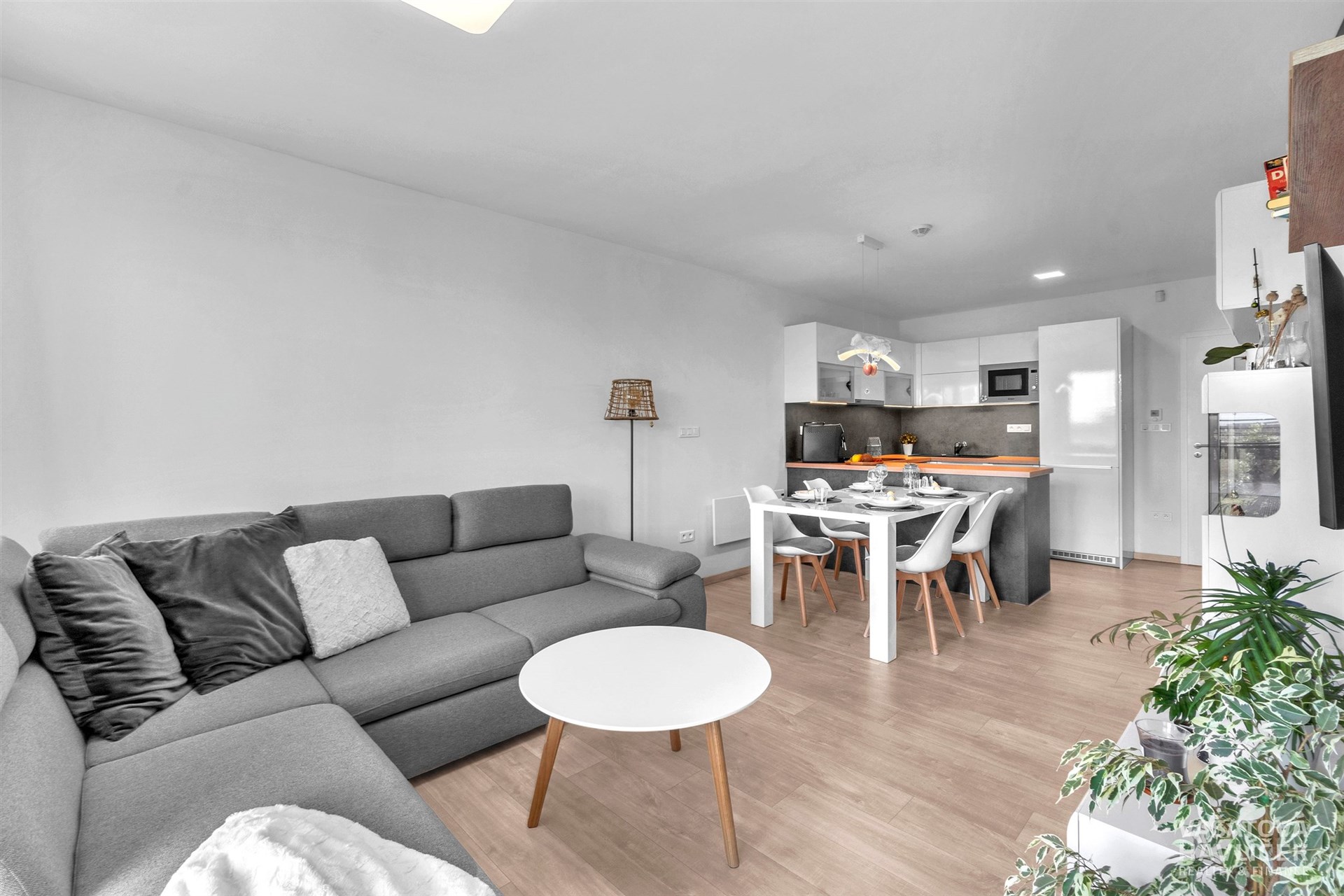 Světlý obývací pokoj s moderní kuchyní, parketová podlaha, velká okna, prostorné uspořádání, stylový design, vhodný pro rodinné bydlení.