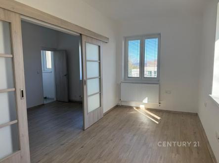 Světlý obývací pokoj s parketovou podlahou, velká okna poskytují přirozené světlo, moderní posuvné dveře oddělují místnosti. | Pronájem bytu, 3+1, 77 m²