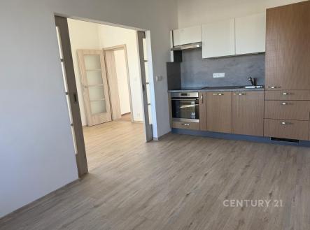 Moderní kuchyň s parketovou podlahou, vestavěnými spotřebiči a dřevěnými skříňkami, vedoucí do světlého obývacího pokoje. | Pronájem bytu, 3+1, 77 m²