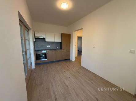 Kuchyňský kout s parketovou podlahou, vestavěnou troubou a moderními skříňkami v světlém interiéru bytové jednotky. | Pronájem bytu, 3+1, 77 m²