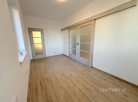 Prostorná ložnice s dřevěnou podlahou, moderní posuvné dveře a světlé stěny vytvářejí pocit vzdušnosti a elegance. | Pronájem bytu, 3+1, 77 m²
