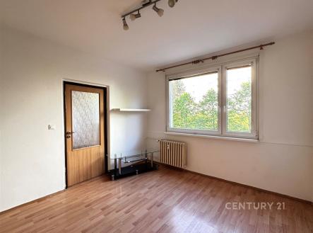 Světlý obývací pokoj s parketovou podlahou a velkými okny, které poskytují dostatek přirozeného světla, v moderním stylu. | Prodej bytu, 1+1, 37 m²