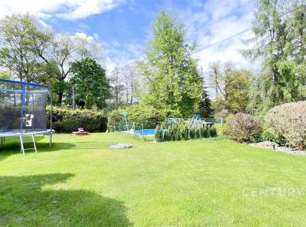 Zahrada s trampolínou a bazénem, udržovaný trávník, obklopená vzrostlou zelení a stromy, ideální pro rodinné aktivity či relaxaci. | Prodej - dům/vila, 145 m²
