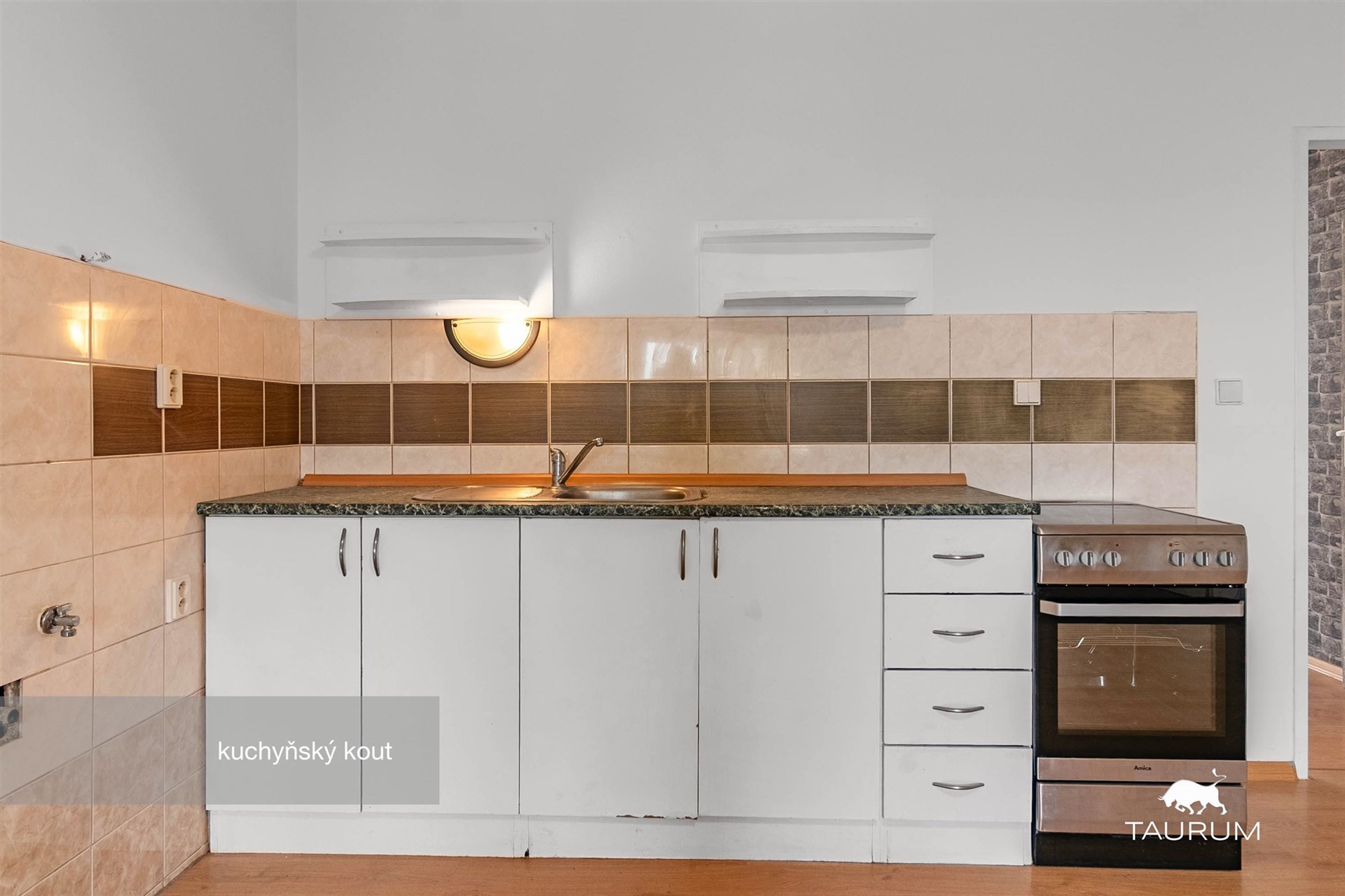 Malý kuchyňský kout s keramickými obklady, dřezem a elektrickým sporákem, parketová podlaha, moderní osvětlení.