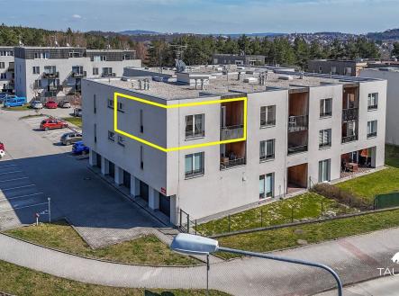 Menší bytový dům s moderním designem, světlou fasádou a plochou střechou, obklopený zelení a asfaltem. | Prodej bytu, 2+kk, 56 m²