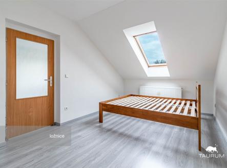 Prostorná ložnice s laminátovou podlahou, velké střešní okno, moderní interiér s dřevěným rámem postele, světlý a vzdušný prostor. | Prodej bytu, 2+kk, 52 m²