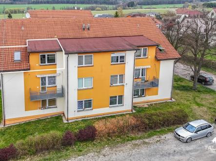 Malý bytový dům s oranžovou fasádou, renovovaná střecha z pálených tašek, klidná lokalita uprostřed zeleně, parkování před domem. | Prodej bytu, 2+kk, 52 m²