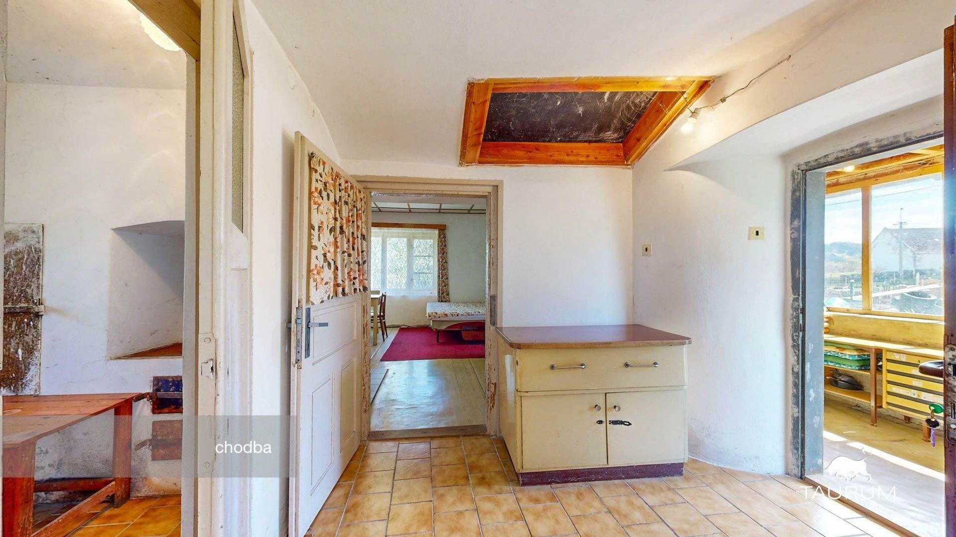 Prostorná chodba s dlažbou, dřevěným stropem a výhledem do zahrady, nabízí možnost rekonstrukce a promyšlený interiér.