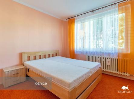 Světlá ložnice s dřevěnou postelí a velkým oknem, oranžové stěny a koberce, moderní vybavení, příjemná atmosféra a dobré osvětlení. | Prodej bytu, 3+1, 58 m²
