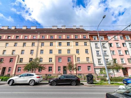 Vícepatrový obytný dům s barevnou fasádou, velkými okny, parkováním před budovou, nacházející se ve městě. | Prodej bytu, 2+kk, 50 m²