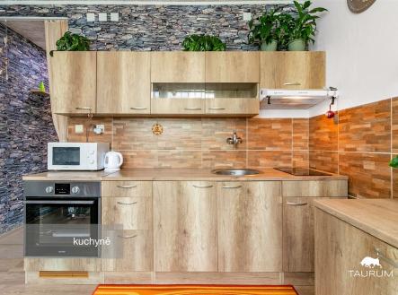 Kuchyň s dřevěnou linkou, moderními spotřebiči a obkladem z kamene. Světlý prostor s parketovou podlahou a dekorativními prvky. | Prodej bytu, 2+1, 63 m²