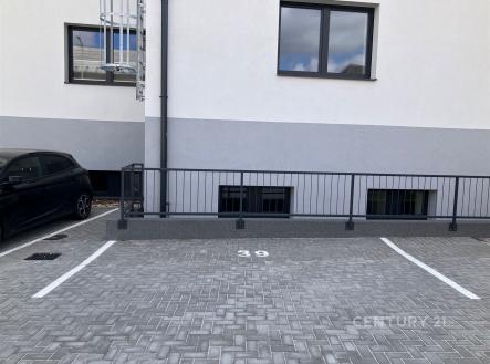 Prázdné parkovací místo s dlažbou, označené číslem 39, vedle moderní budovy. Vhodné pro parkování rezidentů v městské oblasti. | Pronájem - malý objekt/garáž