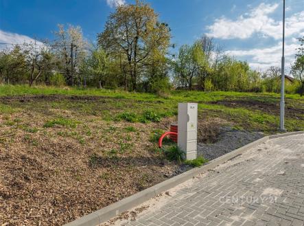 Stavební pozemek se zpevněnou příjezdovou cestou, obklopený zelení a stromy, nabízí klidnou lokalitu pro výstavbu nového domu. | Prodej - pozemek pro bydlení, 1 204 m²