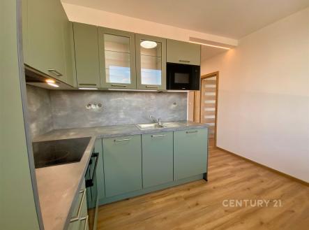 Moderní kuchyň s parketovou podlahou, vestavěnými spotřebiči a světlými skříňkami, nabízí praktický a stylový prostor pro vaření. | Pronájem bytu, 1+1, 30 m²