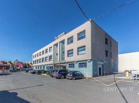 Moderní komerční budova s velkými okny a parkovacími místy. Stavba ve světlých barvách nabízí flexibilní kancelářské prostory. | Pronájem - kanceláře, 152 m²