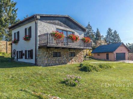Dvoupodlažní dům na velkém pozemku, obložený kamenem, s květinovými truhlíky na balkoně, zelený a klidný okolní prostor. | Prodej - chata/rekreační objekt, 80 m²