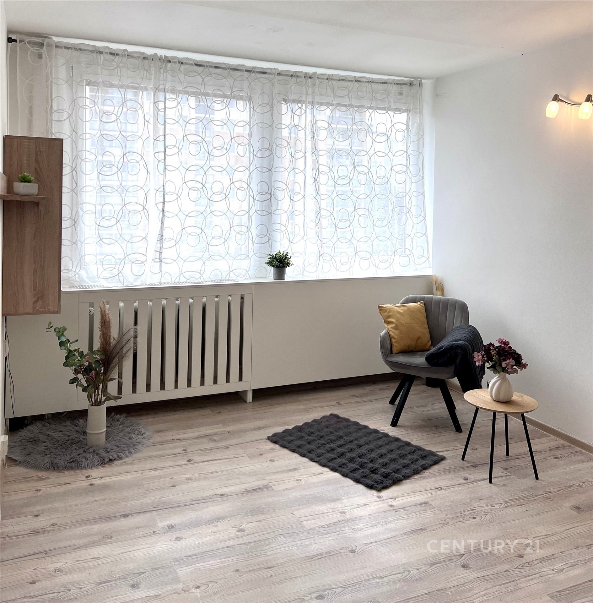 Světlý obývací pokoj s parketovou podlahou, velká okna s moderními závěsy, minimalistický styl, dekorativní rostliny, rekonstrukce.