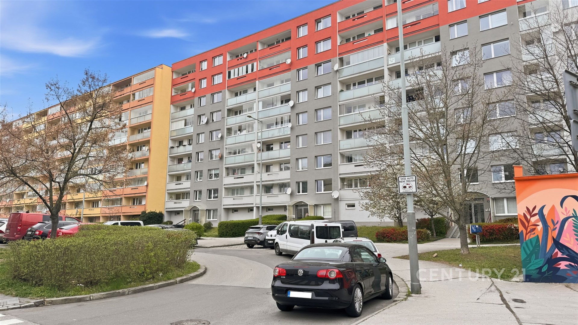 Vícepodlažní bytový dům s balkony, moderní fasáda, městské prostředí.