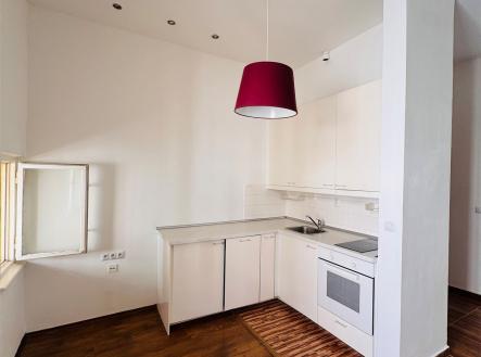 Světlá kuchyň s dřevěnou podlahou, moderními bílými skříňkami a stylovým červeným osvětlením, ideální pro útulné bydlení | Pronájem bytu, 2+kk, 30 m²