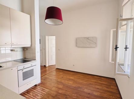Kuchyňský kout s dřevěnou podlahou, světlými skříňkami a velkým oknem, moderní spotřebiče zajišťují pohodlí a útulnost. | Pronájem bytu, 2+kk, 30 m²