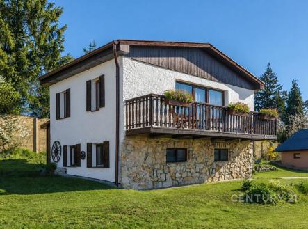 Dvoupatrový rodinný dům s kamenným základem, dřevěným balkónem a velkými okny na klidném venkovském pozemku. | Prodej - chata/rekreační objekt, 80 m²