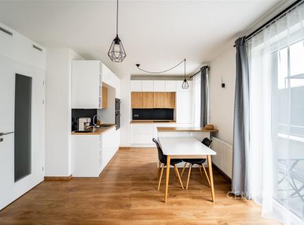 Moderní kuchyň s parketovou podlahou, světlými stěnami a velkými okny. Stylový nábytek a moderní osvětlení dodávají prostoru elegantní atmosféru. | Prodej bytu, 3+kk, 86 m²
