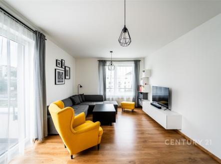Světlý obývací pokoj s parketovou podlahou, velká okna a moderní vybavení. Prostor je elegantní a stylově zařízený s barevnými akcenty. | Prodej bytu, 3+kk, 86 m²