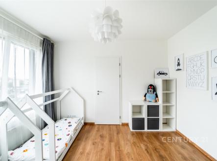 Dětský pokoj s moderním nábytkem, parketovou podlahou a velkými okny, zajišťuje dostatek přirozeného světla. | Prodej bytu, 3+kk, 86 m²
