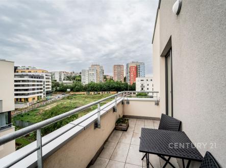 Moderní balkon s dlažbou a výhledem na městskou zástavbu, vybavený elegantním zahradním nábytkem, ideální pro relaxaci | Prodej bytu, 3+kk, 86 m²