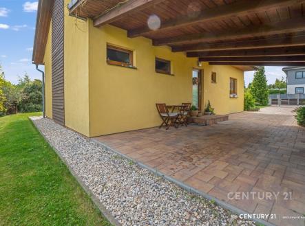 Krytá terasa s dlažbou, dřevěným stropem a posezením, obklopena upravenou zahradou, nabízí klidné místo pro relaxaci. | Prodej - dům/vila, 67 m²