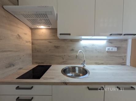 Moderní kuchyň s dřevěnou pracovní deskou, vestavěnými spotřebiči a světlými skříňkami. | Pronájem bytu, 2+1, 54 m²