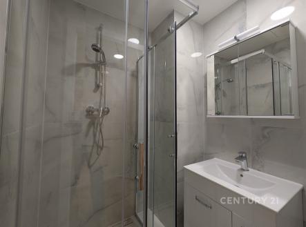 Moderní koupelna s proskleným sprchovým koutem, světlými dlažbami a elegantním umyvadlem, ideální pro moderní bydlení. | Pronájem bytu, 2+1, 54 m²
