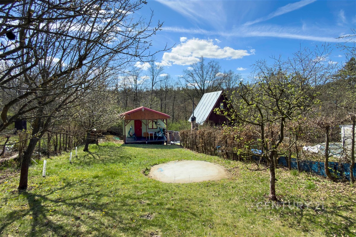 Rozlehlá zahrada s trávníkem a ovocnými stromy, malý dřevěný zahradní domek, klidná lokalita vhodná pro rekreaci.