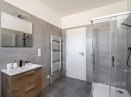 Moderní koupelna s dlažbou, sprchovým koutem a dřevěnou skříňkou. Světlé a rekonstruované prostory s topným žebříkem poskytují komfort. | Prodej - dům/vila, 98 m²