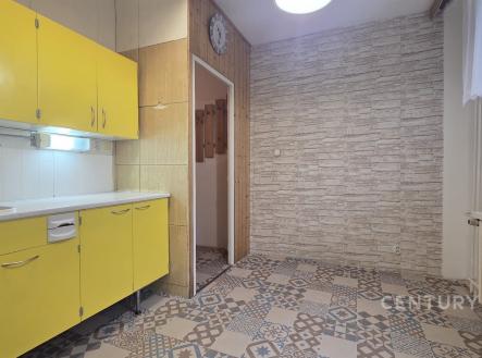 Kuchyň v retro stylu s výraznými žlutými skříňkami, dlažbou s vintage vzorem a světlými kamennými obklady na zdech | Pronájem bytu, 1+1, 33 m²