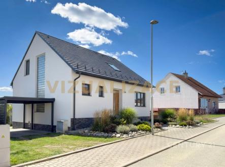 Moderní rodinný dům s černou střešní krytinou, světlou fasádou a upravenou zahradou. Disponuje boční terasou a přístřeškem pro auto. | Prodej - dům/vila, 133 m²
