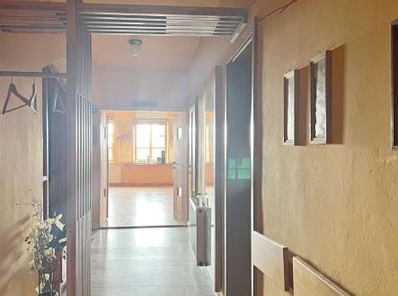 Chodba s dlažbou, vestavěnými skříněmi a velkými okny, která propouštějí světlo, působí útulně a moderně. | Pronájem - obchodní prostor, 299 m²