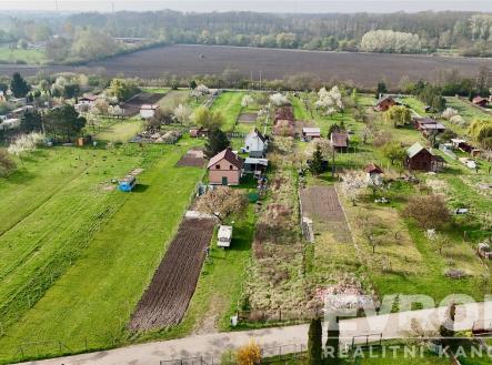 Letecký pohled na rozlehlou zahradu s travnatými plochami a několika malými stavbami, obklopenou zelení a blízkým lesem. | Prodej - pozemek, zemědělská půda, 1 539 m²