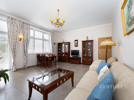 Světlý obývací pokoj s dlažbou, velkými okny a klasickým nábytkem, moderní dekorace a prostorný interiér. | Prodej - dům/vila, 249 m²