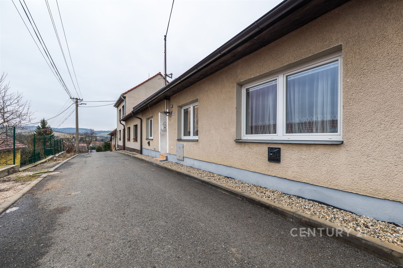 Fasáda rodinného domu s moderními okny na klidné ulici nabízí pěkný výhled na okolní krajinu. Výborný stav a upravené okolí.