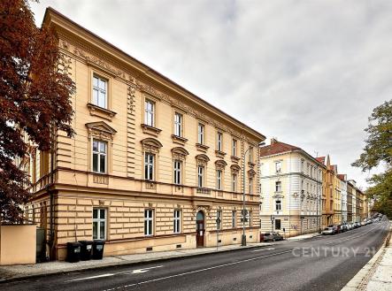 Historická fasáda bytového domu s tradičními architektonickými prvky na klidné ulici, renovovaný exteriér s okny do ulice, udržované okolí. | Pronájem bytu, 3+kk, 134 m²