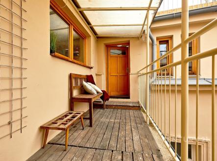 Zrekonstruovaný balkon s dřevěnou podlahou, minimalistickým dřevěným nábytkem a velkými okny, poskytujícími dostatek přirozeného světla. | Pronájem bytu, 3+kk, 134 m²