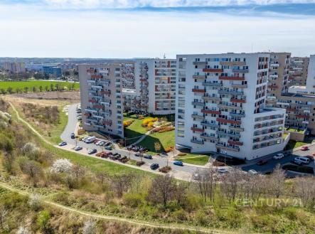 Panelový bytový komplex s moderními fasádami, obklopený zelenými plochami a parkovištěm, nabízí klidné bydlení na okraji města. | Pronájem bytu, 2+kk, 48 m²