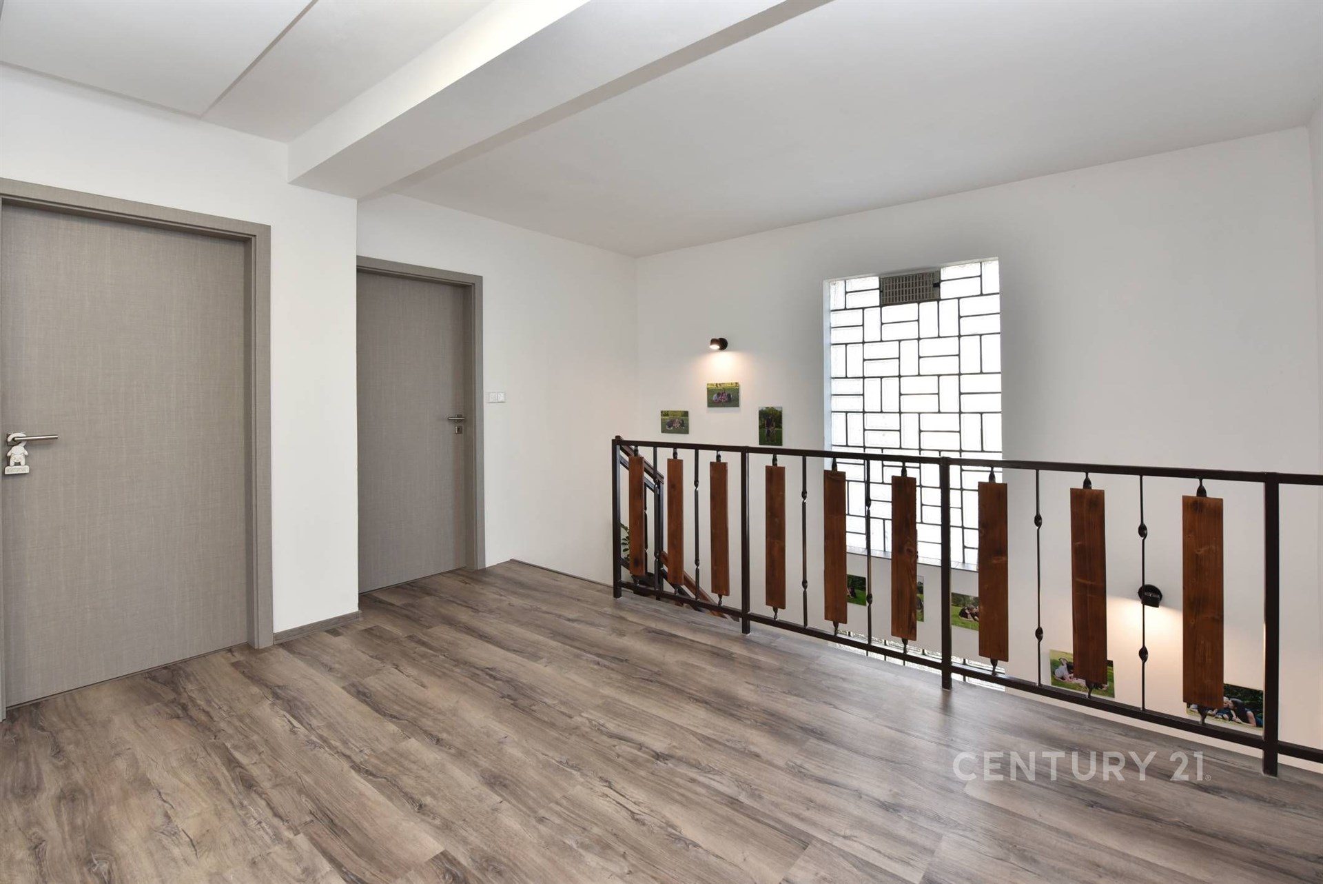 Chodba s moderním laminátovou podlahou a stylovým zábradlím, dveře v neutrálním odstínu, prostorný a světlý interiér.