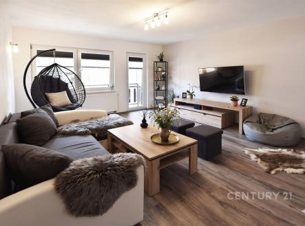 Světlý obývací pokoj s moderním designem, dřevěnou podlahou a velkými okny, vybavený pohodlnou sedací soupravou a nástěnnou televizí. | Prodej - dům/vila, 273 m²