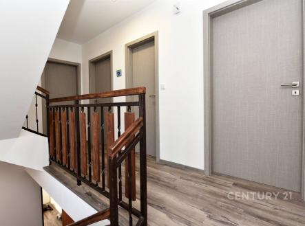 Chodba s dřevěným zábradlím a světlou podlahou, moderní dveře vytvářejí elegantní vzhled, rekonstrukce v nadstandardním provedení | Prodej - dům/vila, 273 m²