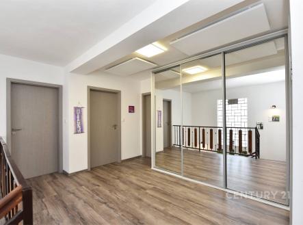 Chodba s laminátovou podlahou, vestavěné skříně a moderní design, světlý prostor díky velkým oknům a minimalistické osvětlení. | Prodej - dům/vila, 273 m²