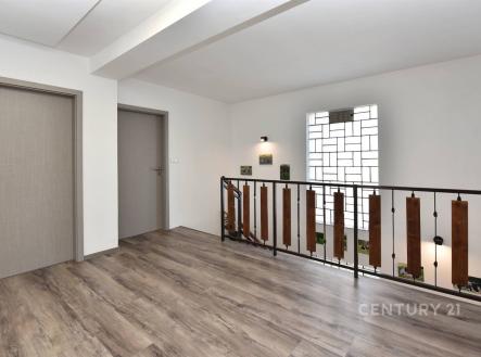 Chodba s moderním laminátovou podlahou a stylovým zábradlím, dveře v neutrálním odstínu, prostorný a světlý interiér. | Prodej - dům/vila, 273 m²