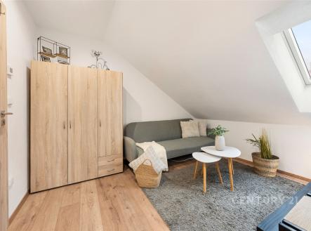 Podkrovní obývací pokoj s parketovou podlahou, střešními okny a moderním nábytkem, poskytující útulný a světlý prostor pro relaxaci. | Prodej bytu, 3+kk, 45 m²